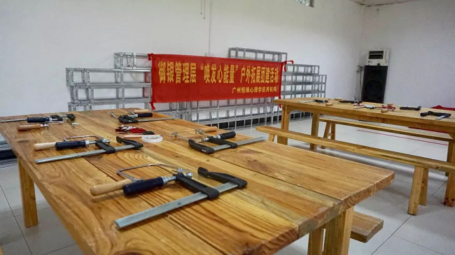 　測試不是目的，在香草拓展基地的冠軍營地，培訓(xùn)機構(gòu)還特別請來了黃大仙為大家解讀迷津，讓參訓(xùn)的管理人員重新認(rèn)識心底的自己，同時理解溝通中可能出現(xiàn)的障礙，與此同時，還借助測試引導(dǎo)管理人員轉(zhuǎn)換角度、換位思考，借此提高溝通的效能。不僅如此，黃大仙還在介紹過程中為參訓(xùn)人員提供了一些提升管理的溝通小秘籍。     經(jīng)歷匠人精神     　　沒有真正的經(jīng)歷，又談何真正的理解與認(rèn)識。管理人員來自不同的部門、不同的領(lǐng)域，為了加深理解與認(rèn)識，培訓(xùn)進入了第二個環(huán)節(jié)——體驗?zāi)舅嚬ぷ鞣?。每人一個F夾、一把手持鋸，一到兩塊木板、幾幅看似有些朦朧的造型圖、鉛筆、剪刀、砂紙，還有作品任務(wù)書，工作坊正式啟動。